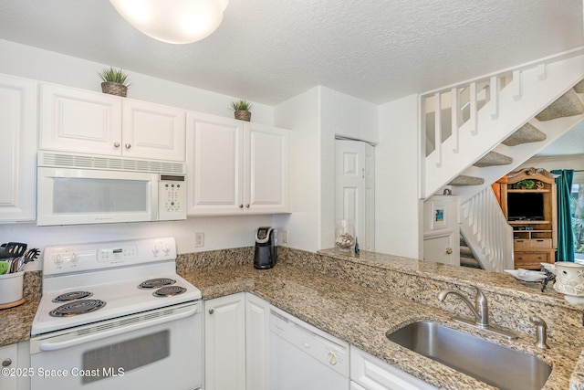 kitchen featuring light stone counters, white appliances, white cabinetry, and a sink