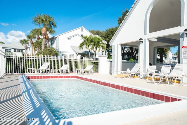 community pool with a patio area and fence