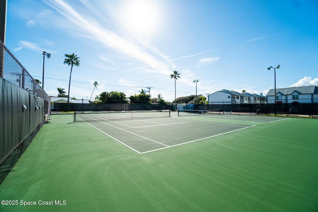 view of tennis court with a residential view and fence