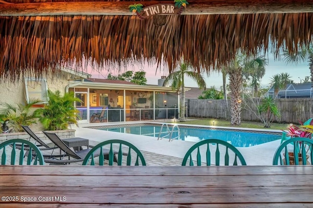 pool at dusk featuring a sunroom