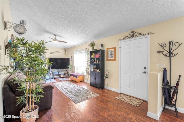 living area with baseboards, a textured ceiling, a ceiling fan, and wood finished floors