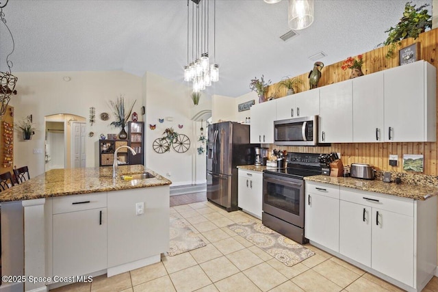 kitchen with stainless steel appliances, white cabinetry, hanging light fixtures, and a sink