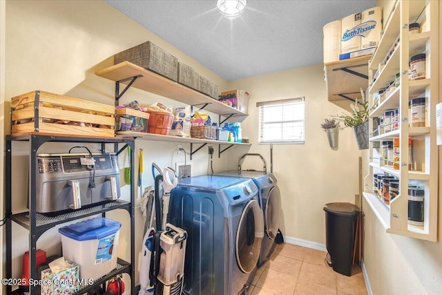 laundry room featuring light tile patterned floors, a textured ceiling, laundry area, separate washer and dryer, and baseboards