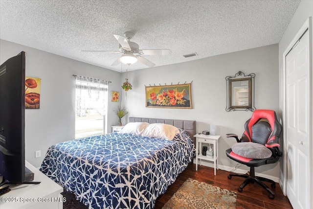 bedroom with baseboards, dark wood finished floors, a ceiling fan, a textured ceiling, and a closet