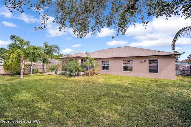 rear view of house featuring stucco siding, a fenced backyard, central AC unit, and a yard