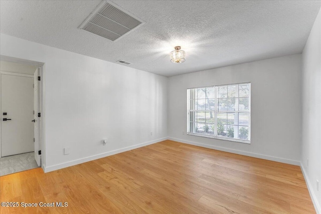 empty room with a textured ceiling and hardwood / wood-style floors