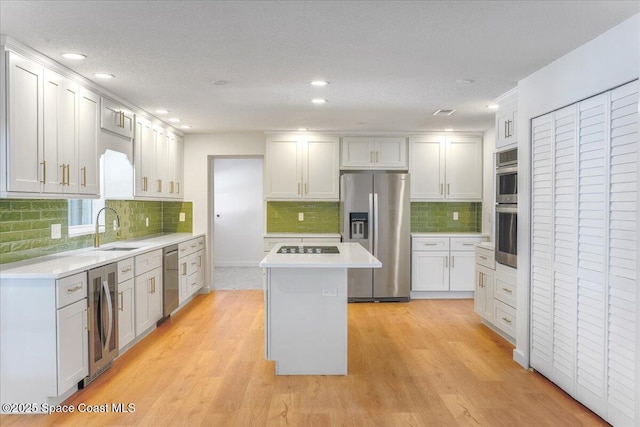 kitchen featuring a kitchen island, sink, stainless steel appliances, and white cabinetry