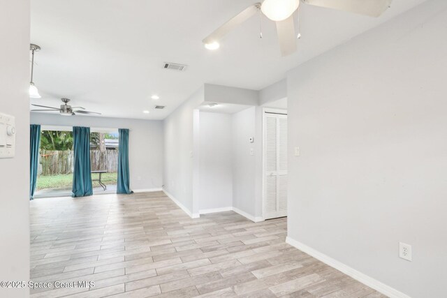 unfurnished room with light wood-style flooring, a ceiling fan, visible vents, and baseboards