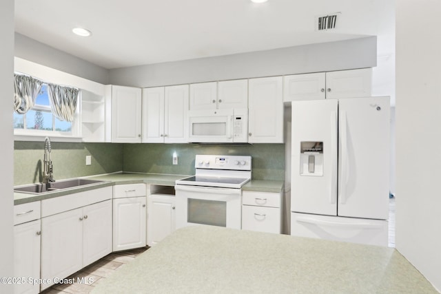 kitchen featuring light countertops, white appliances, a sink, and white cabinetry