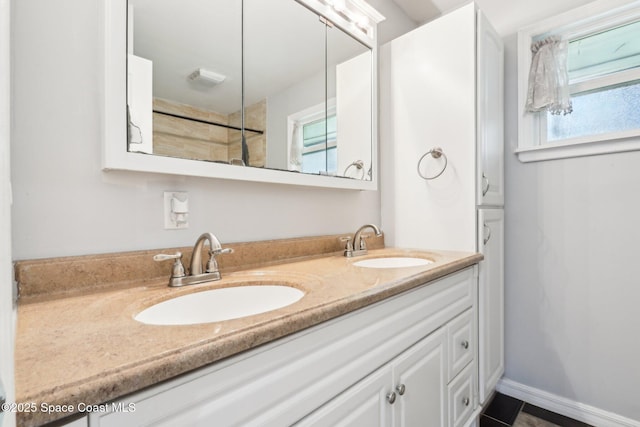 full bath featuring double vanity, a sink, and baseboards