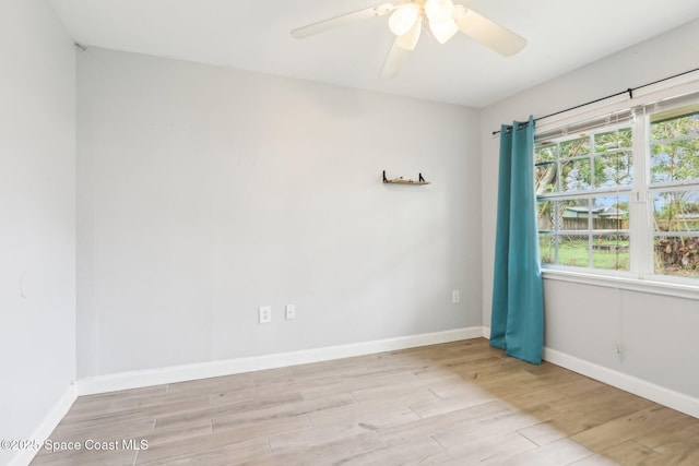 spare room featuring light wood-style floors, baseboards, and a ceiling fan