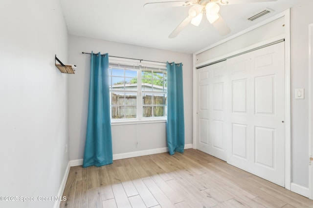 unfurnished bedroom featuring light wood-type flooring, baseboards, visible vents, and a closet