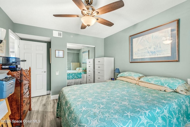 bedroom with visible vents, baseboards, a ceiling fan, light wood-style floors, and a closet