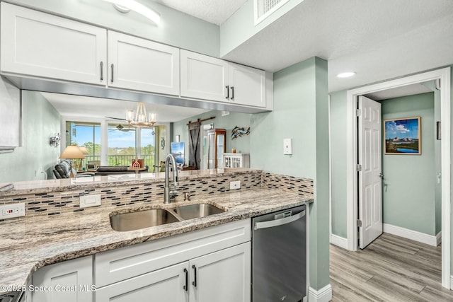 kitchen with light wood finished floors, dishwasher, light stone counters, white cabinetry, and a sink