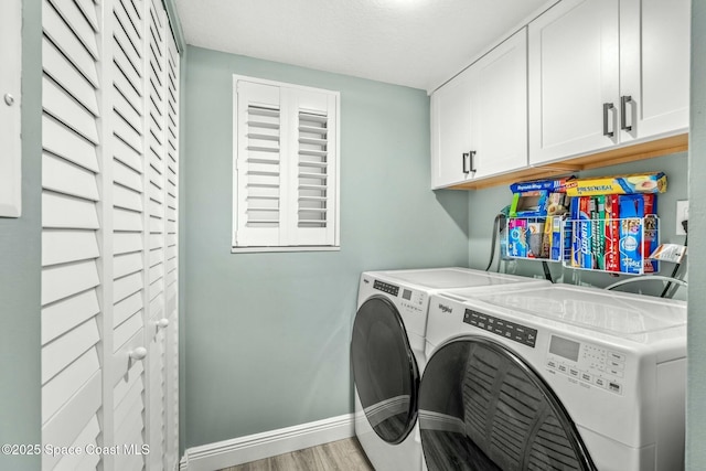 washroom featuring cabinet space, washer and clothes dryer, baseboards, and wood finished floors