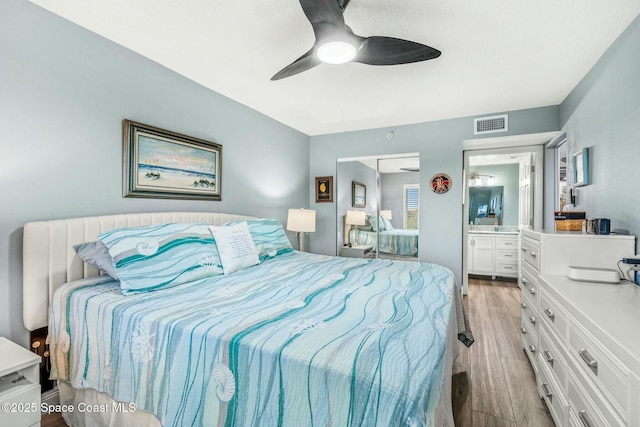 bedroom with wood finish floors, ensuite bath, visible vents, and a ceiling fan