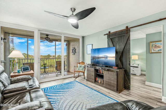 living area with expansive windows, ceiling fan, baseboards, and light wood-style floors