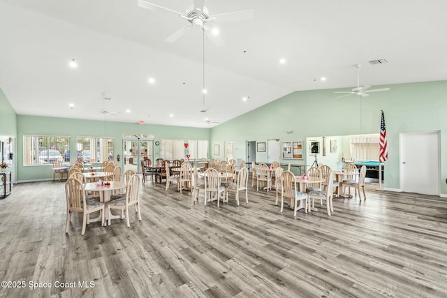 dining room with high vaulted ceiling, light wood-style flooring, visible vents, and a ceiling fan