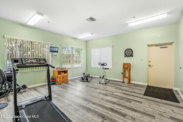 workout room featuring wood finished floors, visible vents, and baseboards