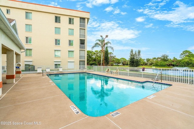 pool featuring a patio, a water view, and fence