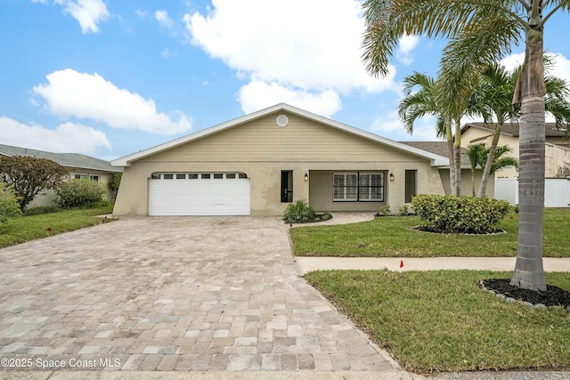 single story home featuring decorative driveway, an attached garage, stucco siding, and a front yard