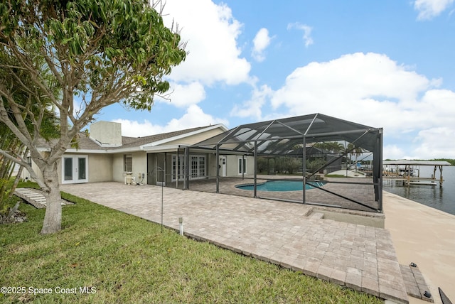 view of swimming pool with a yard, a patio, french doors, and a water view