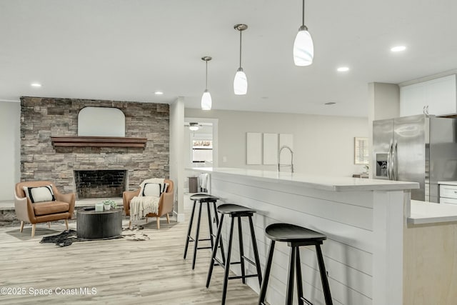 kitchen featuring stainless steel fridge, open floor plan, decorative light fixtures, light countertops, and white cabinetry