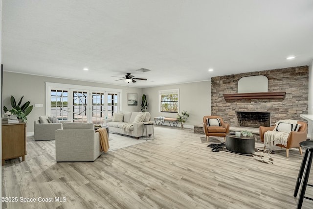 living area with baseboards, a fireplace, light wood-style flooring, and a healthy amount of sunlight