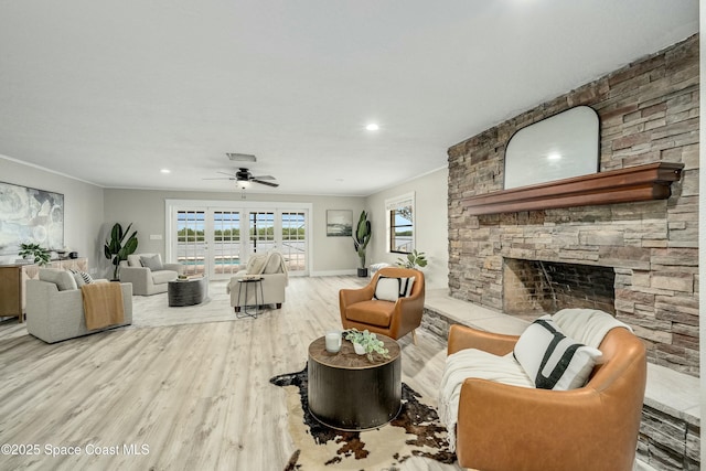 living area with a stone fireplace, recessed lighting, a ceiling fan, light wood finished floors, and crown molding