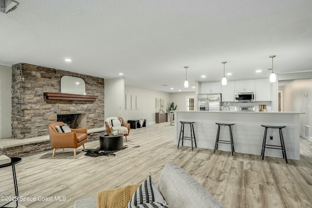 kitchen featuring a breakfast bar, white cabinetry, open floor plan, appliances with stainless steel finishes, and decorative light fixtures