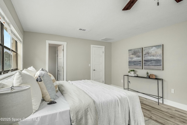 bedroom with visible vents, light wood-style flooring, a ceiling fan, connected bathroom, and baseboards