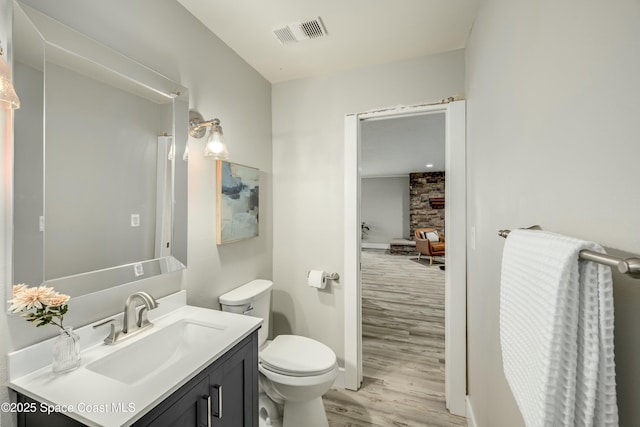 bathroom with baseboards, visible vents, toilet, wood finished floors, and vanity