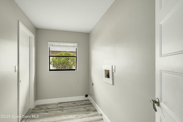 washroom with hookup for a washing machine, hookup for an electric dryer, laundry area, light wood-style floors, and baseboards