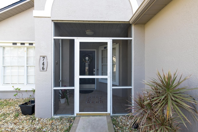 doorway to property featuring stucco siding