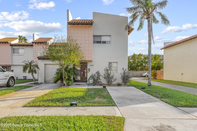 view of front facade with concrete driveway, a front lawn, a tile roof, and stucco siding