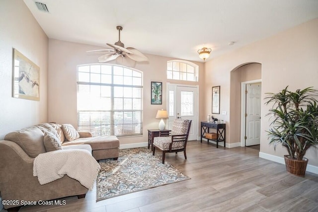 living area with baseboards, visible vents, arched walkways, a ceiling fan, and wood finished floors