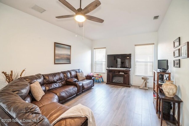 living room with lofted ceiling, light wood-style flooring, and visible vents