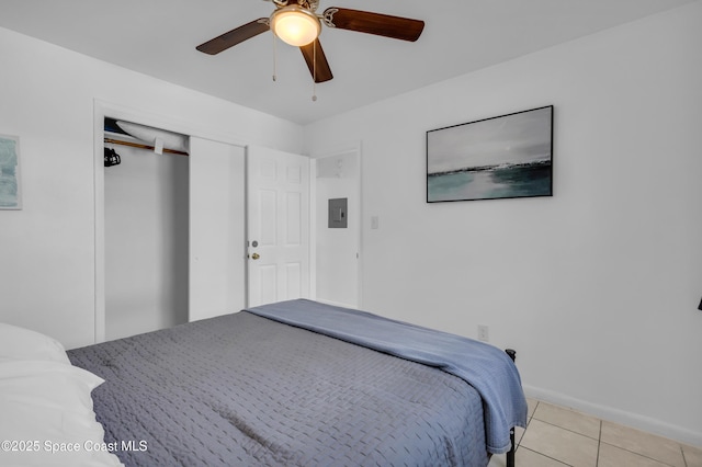 bedroom with light tile patterned floors, a closet, ceiling fan, electric panel, and baseboards