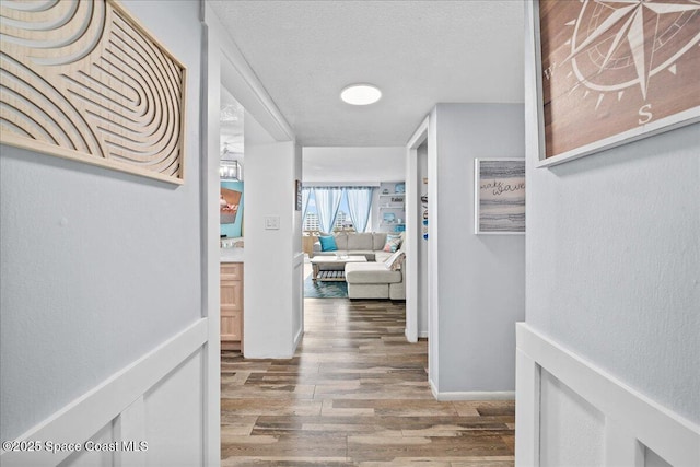 hall with a textured ceiling and wood finished floors