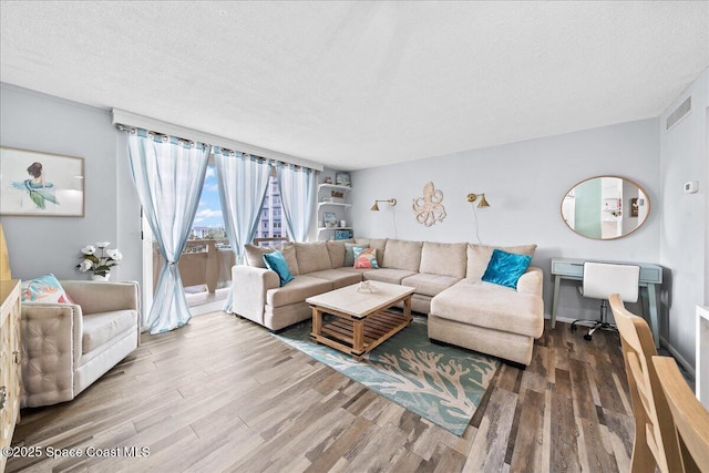 living room with a textured ceiling, visible vents, and wood finished floors