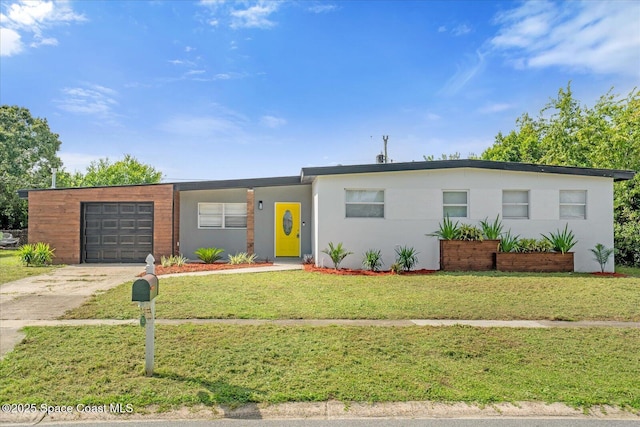 view of front facade featuring an attached garage, concrete driveway, a front yard, and stucco siding