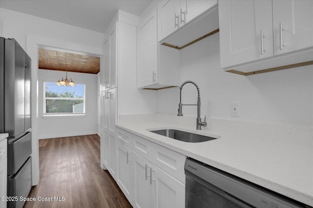 kitchen with dishwasher, freestanding refrigerator, an inviting chandelier, white cabinetry, and a sink