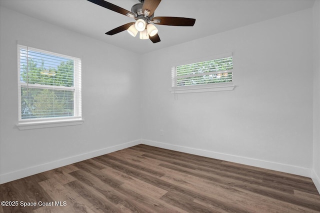 spare room with dark wood-type flooring, a healthy amount of sunlight, and baseboards