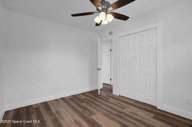 unfurnished bedroom with dark wood-style floors, a closet, visible vents, and baseboards