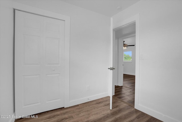 unfurnished bedroom with a closet, baseboards, and wood finished floors