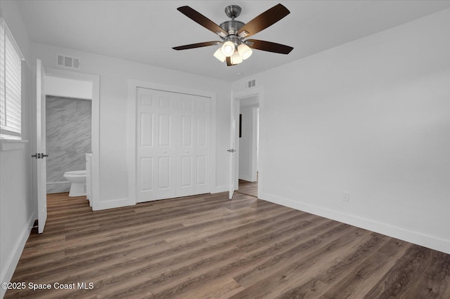 unfurnished bedroom with dark wood-type flooring, a closet, visible vents, and baseboards