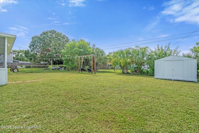 view of yard featuring fence, an outdoor structure, and a storage unit