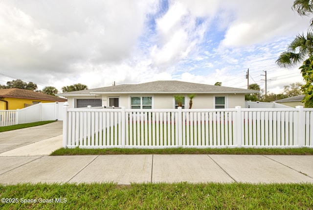 view of front of house featuring a fenced front yard, concrete driveway, a garage, and stucco siding