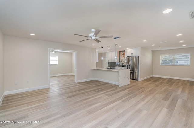 kitchen featuring white cabinets, open floor plan, a peninsula, stainless steel refrigerator with ice dispenser, and pendant lighting