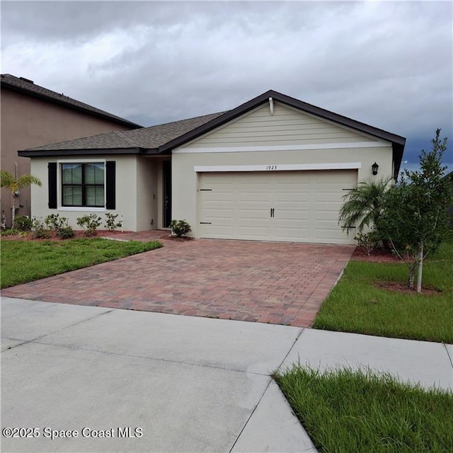 single story home with decorative driveway, an attached garage, a front yard, and stucco siding